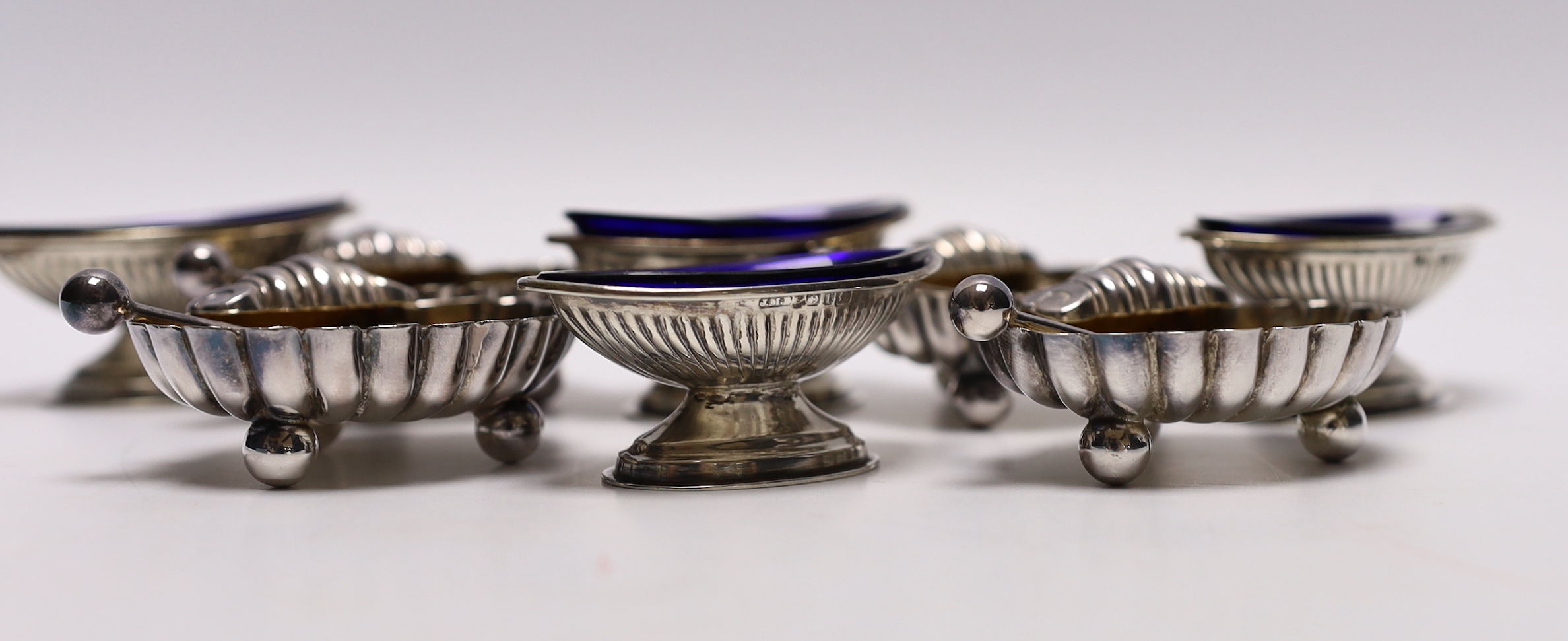 A set of four Victorian elliptical shaped silver pedestal salts, Birmingham, 1891, 58mm, with blue glass liners and a set of four silver plated salts.